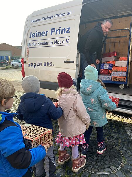 WESSLING and the children from the Zappelkiste daycare center load Christmas packages for the Little Prince campaign.