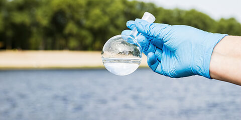 WESSLING Probenehmer hält Wasserprobe in der Hand - Analytik und Beratungsdienstleistungen laufen bei WESSLING Hand in Hand.