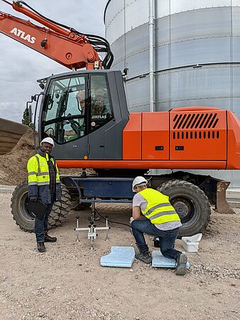 Justine Olweny (left) is conducting static load plate compression tests to determine the compressive strength or load-bearing capacity of soils.